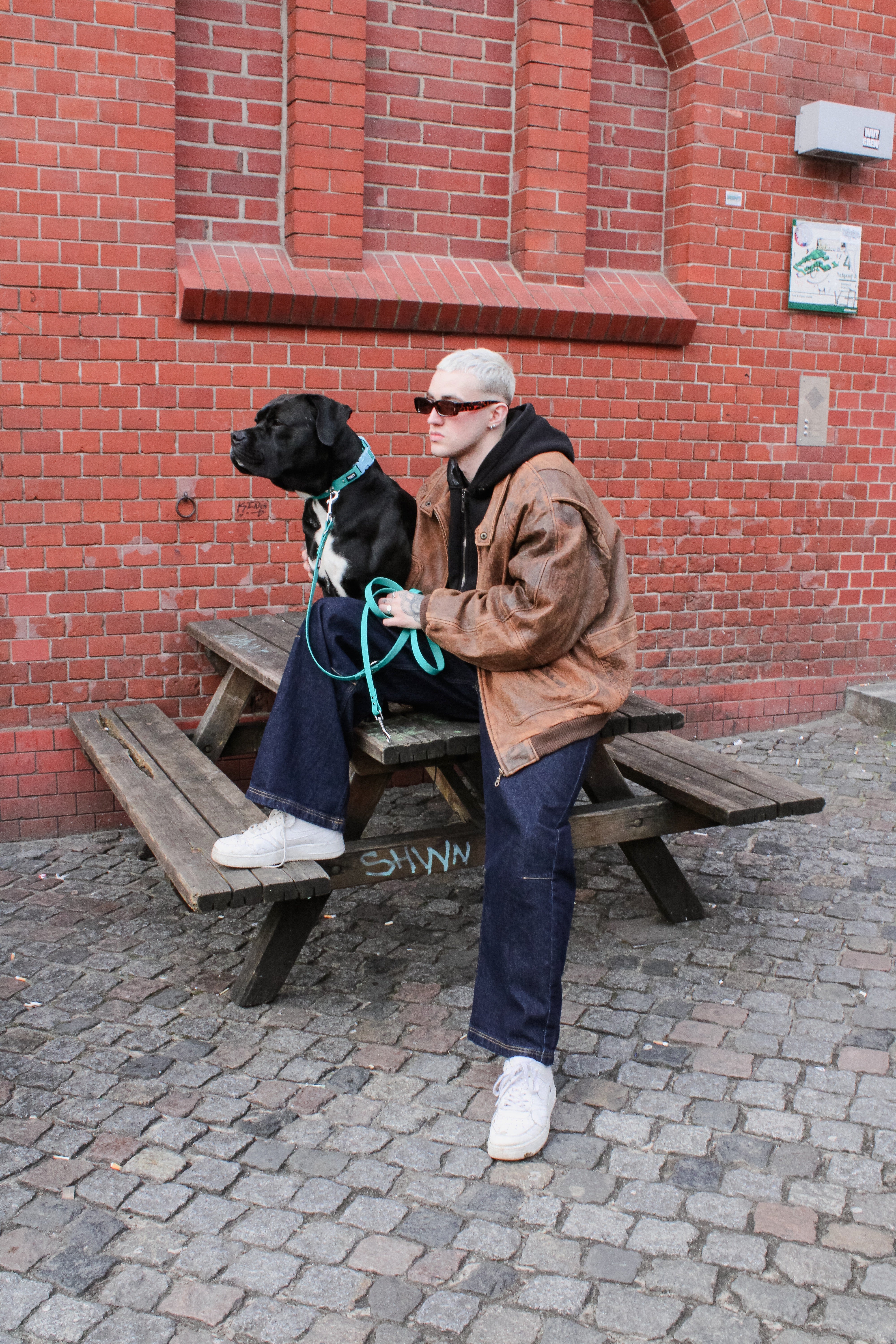 Schwarzer Hund mit männlichem Model. Hund trägt veganes Set in türkis von SUNNY BERLIN